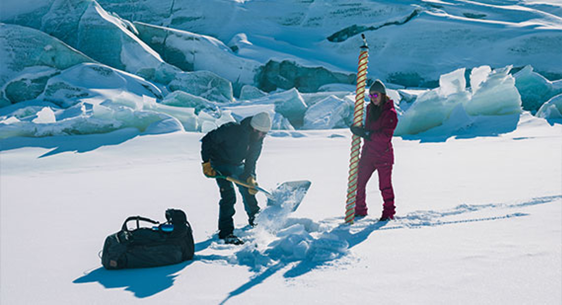 two people wearing Fjallraven Greenland apparel digging in the snow
